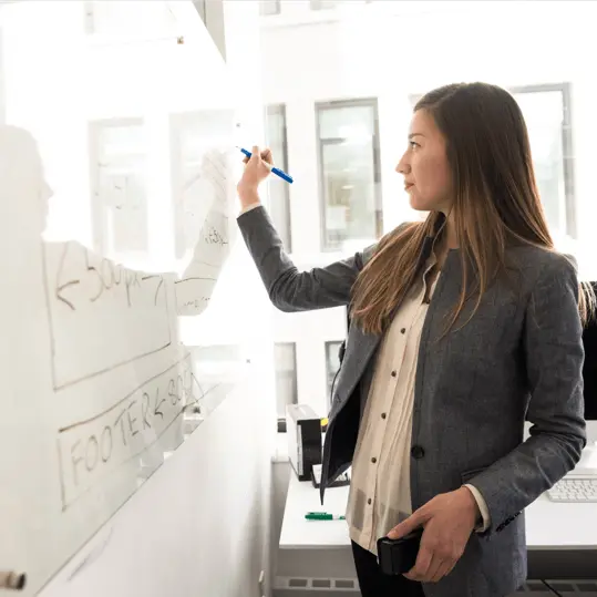 a woman writing on a whiteboard